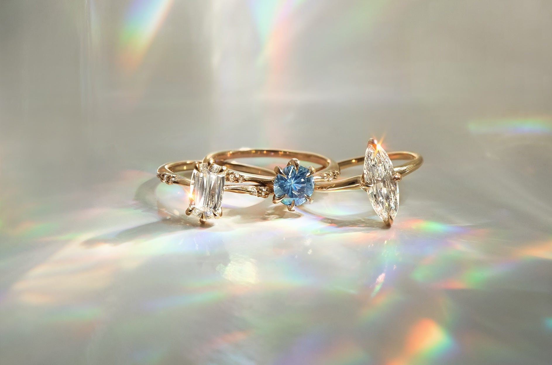 Three handmade solid gold rings against an off-white background.