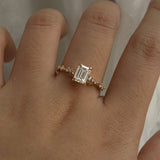 A delicate and ethereal hand-carved one of a kind "Daphne" style engagement ring by Laurie Fleming Jewellery. The ring features a 1.01ct emerald cut diamond with rose and brilliant cut diamond accents on the band in 14k yellow gold. The ring is worn on a hand posed in front of some draped gossamer silk fabric.