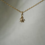 An Anemone flower charm, with round brilliant diamond petals and a rose cut salt and pepper diamond centre, hanging from a 1mm cable chain with smooth oval links. Handmade in Toronto by Laurie Fleming Jewellery.
