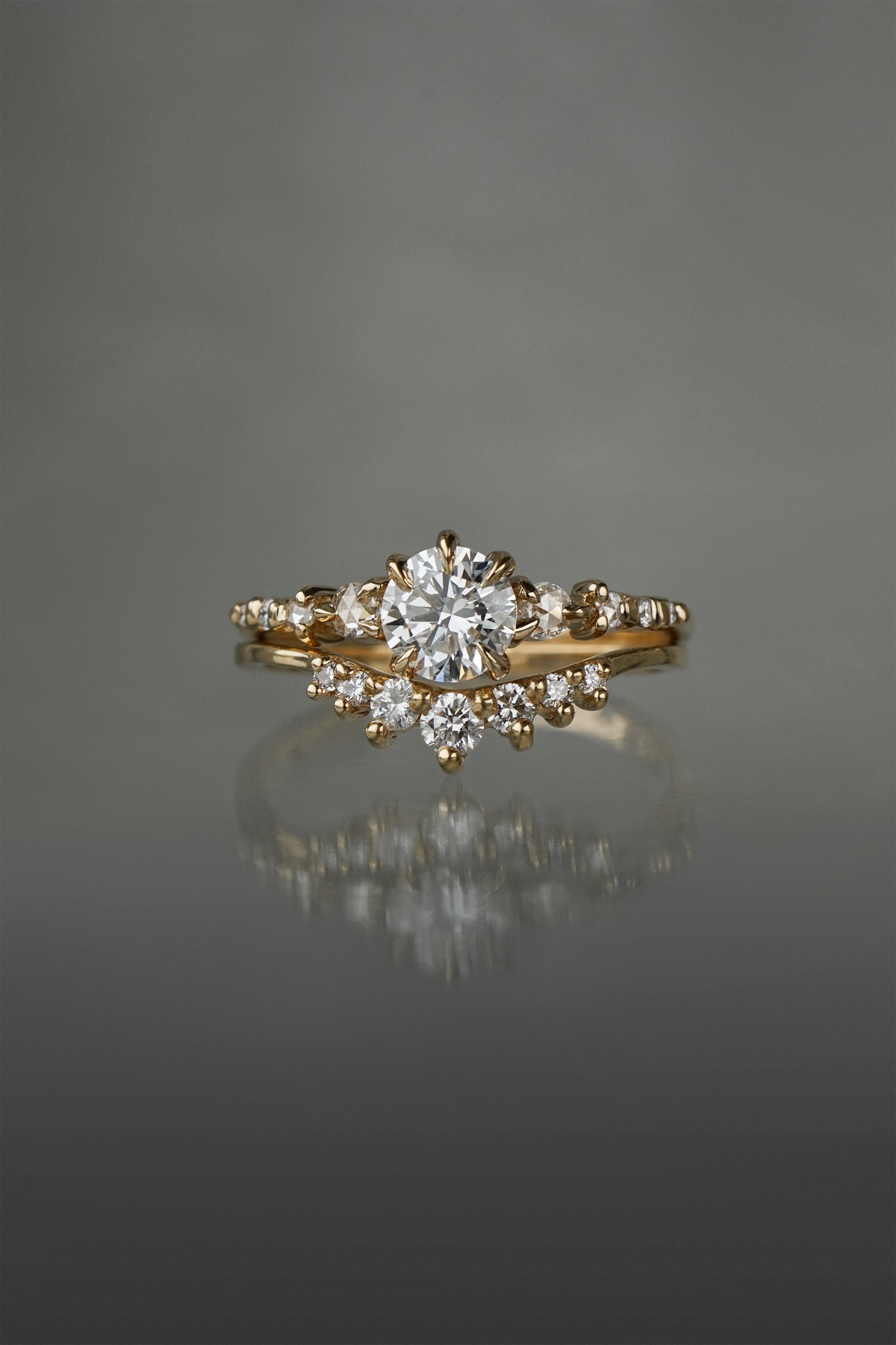 A Cyndra Ring, Supreme with a 0.50-0.55ct lab grown diamond centre on a 14k yellow gold band. The band features a combination of rose cut and brilliant cut diamond accents. The ring is stacked on top of a Brilliant Diamond Beacen Ring, both by Laurie Fleming Jewellery.