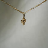 A miniature patch of hand-carved clovers, including a lucky four-leaf clover, as a charm, hanging from a 1mm cable chain with smooth oval links. Handmade in Toronto by Laurie Fleming Jewellery.