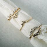 A roll of fabric holding multiple rings by Laurie Fleming Jewellery. From left to right: Marquise Diamond Jasmine Ring, Rose Cut Diamond Aika Ring, Salt and Pepper Diamond Aika Ring, Rose Cut Diamond Beacen Ring, and Salt and Pepper Diamond Beacen Ring.
