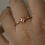 A delicate hand-carved one of a kind "Ilona" style engagement ring by Laurie Fleming Jewellery. The ring features a rose cut pink sapphire centre, a tapered knife-edge band, and small diamond accents on the band shoulders. The ring is worn on a hand against a light grey background.