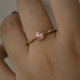 A delicate hand-carved one of a kind "Ilona" style engagement ring by Laurie Fleming Jewellery. The ring features a rose cut pink sapphire centre, a tapered knife-edge band, and small diamond accents on the band shoulders. The ring is worn on a hand against a light grey background.