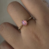 A delicate hand-carved one of a kind "Ilona" style engagement ring by Laurie Fleming Jewellery. The ring features a silky and opalescent rose cut oval pink sapphire centre, a tapered knife-edge band, and small diamond accents on the band shoulders. The ring is worn on a hand against a light grey background.