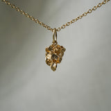 A miniature hand-carved hellebore flower charm,  hanging from a 1mm cable chain with smooth oval links. Handmade in Toronto by Laurie Fleming Jewellery.