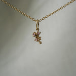 A miniature cluster of lilac flowers with pink sapphires in a charm,  hanging from a 1mm cable chain with smooth oval links. Handmade in Toronto by Laurie Fleming Jewellery.