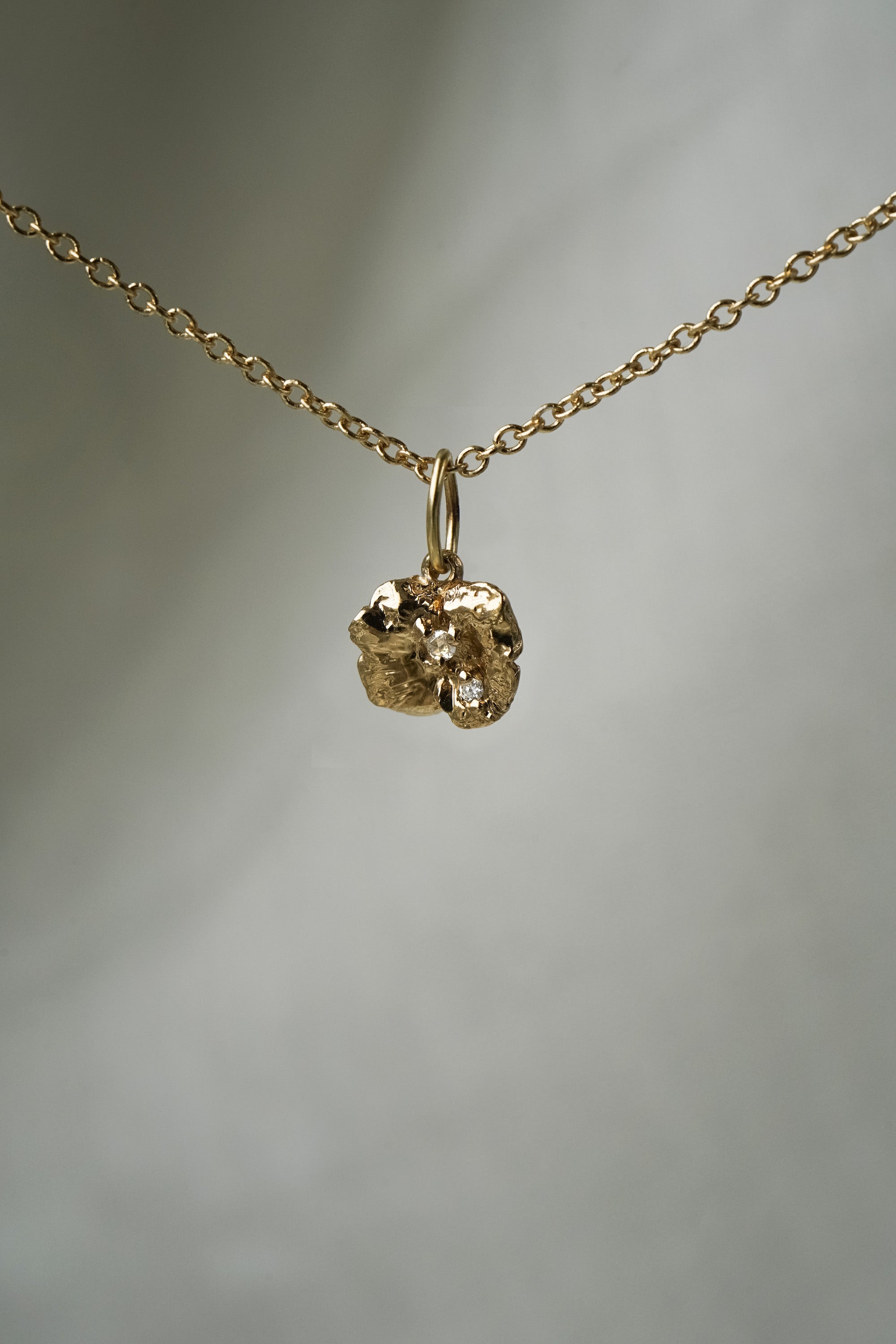A solid gold hand-carved lily pad charm with brilliant and rose cut diamond dew, hanging from a 1mm cable chain with smooth oval links. Handmade in Toronto by Laurie Fleming Jewellery.