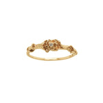 A stock photo of the solid gold "Pansy Signet" ring by Laurie Fleming Jewellery. The ring features hand-carved delicate petals encircling the band, with a tiny pansy flower at the centre, which has a customizable centre stone (pictured with a diamond, available in all birthstones). The ring is on a white background.