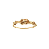 A stock photo of the solid gold "Pansy Signet" ring by Laurie Fleming Jewellery. The ring features hand-carved delicate petals encircling the band, with a tiny pansy flower at the centre, which has a customizable centre stone (pictured with a diamond, available in all birthstones). The ring is on a white background.