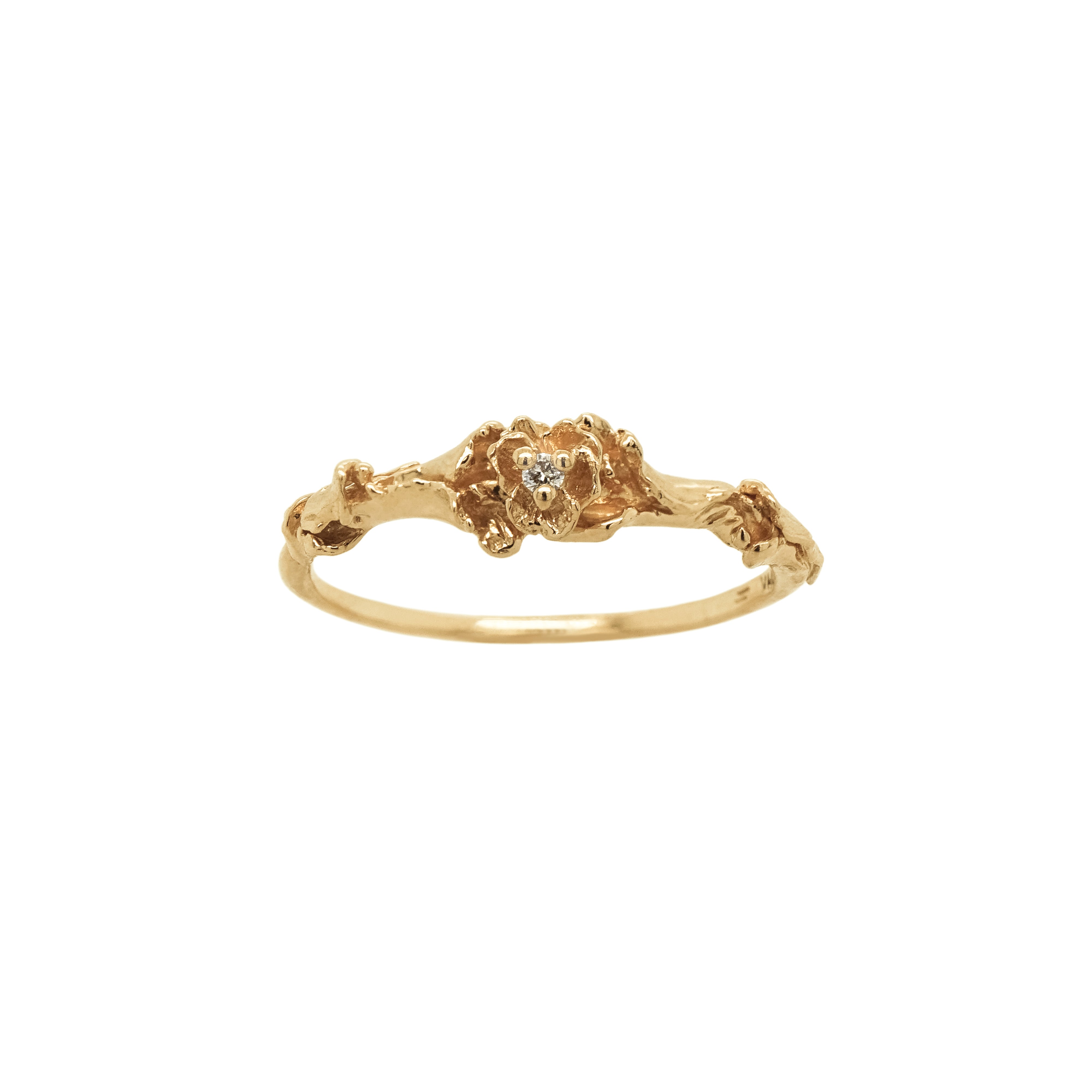 A stock photo of the solid gold "Pansy Signet" ring by Laurie Fleming Jewellery. The ring features hand-carved delicate petals encircling the band, with a tiny pansy flower at the centre, which has a customizable centre stone (pictured with a diamond, available in all birthstones). The ring is on a white background.