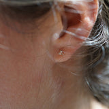 A close up of an ear wearing a Selene Stud earring by Laurie Fleming Jewellery, which features a rose cut diamond held in three delicate claw-shaped prongs.