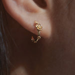 Close-up of an ear wearing a Laurie Fleming Jewellery "Small Buttercup Hoop" earring, featuring petite hand-carved buttercup flowers with a yellow sapphire centre.