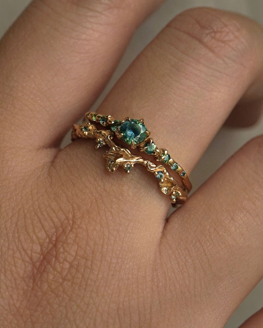 A hand wearing two rings stacked together. From top to bottom: Sapphire Cyndra Ring, Supreme, and Sapphire Evening Fleur Ring