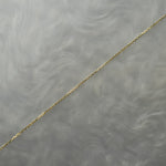 0.68mm super fine and delicate diamond-cut cable chain necklace for charms or pendants.  The chain is against a grey background with swirling patterns.