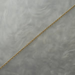 1mm fine and delicate cable chain with smooth oval links in solid 14k gold, perfect for wearing on its own or with charms or pendants. The chain is against a grey background with swirling patterns.