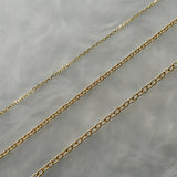 Three delicate solid gold chains laid out on a grey background with swirling patterns. From top to bottom: 0.68mm diamond-cut chain, 1mm petite smooth oval chain, 1.4mm smooth oval chain.