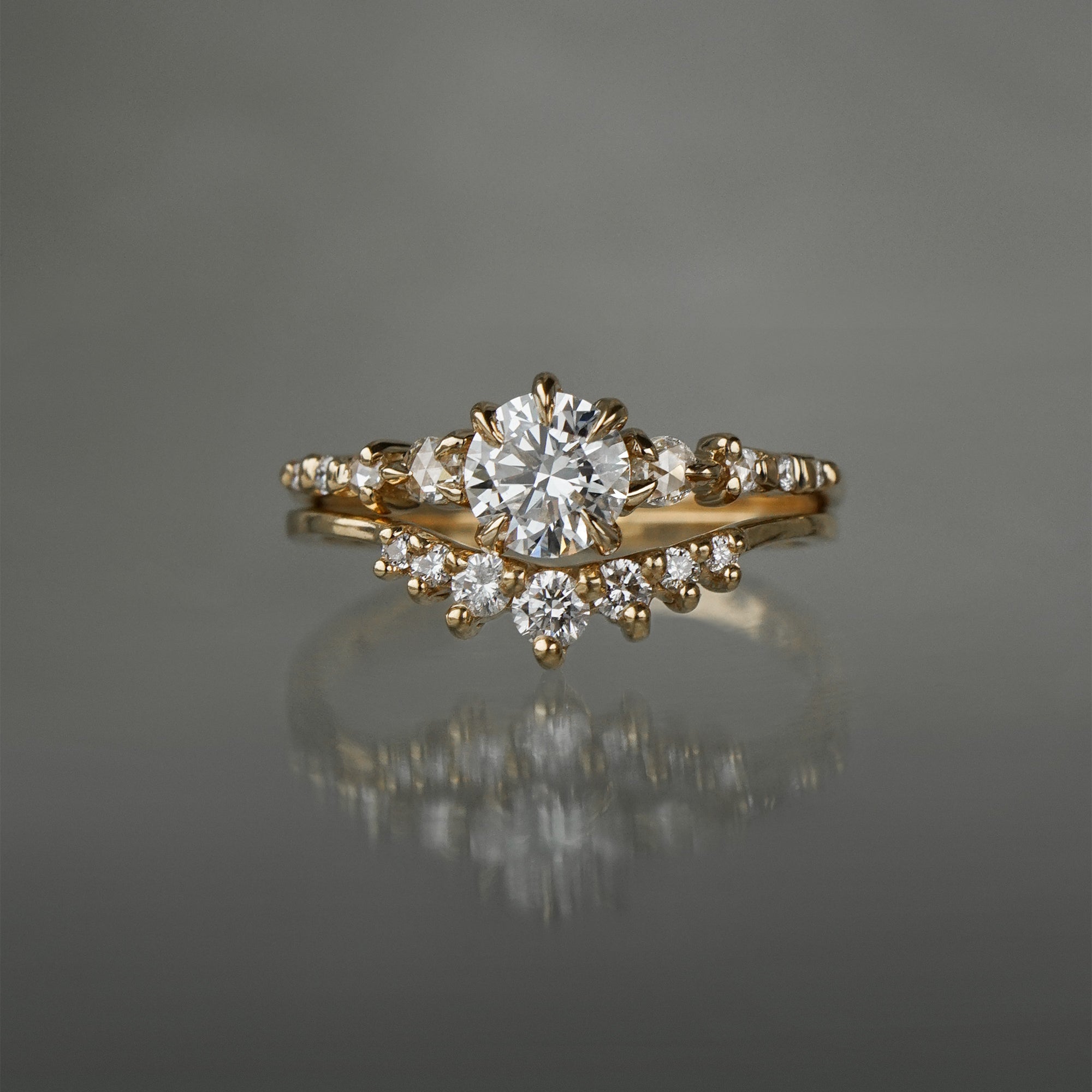 A Cyndra Ring, Supreme with a 0.50-0.55ct lab grown diamond centre on a 14k yellow gold band. The band features a combination of rose cut and brilliant cut diamond accents. The ring is stacked on top of a Brilliant Diamond Beacen Ring, both by Laurie Fleming Jewellery.