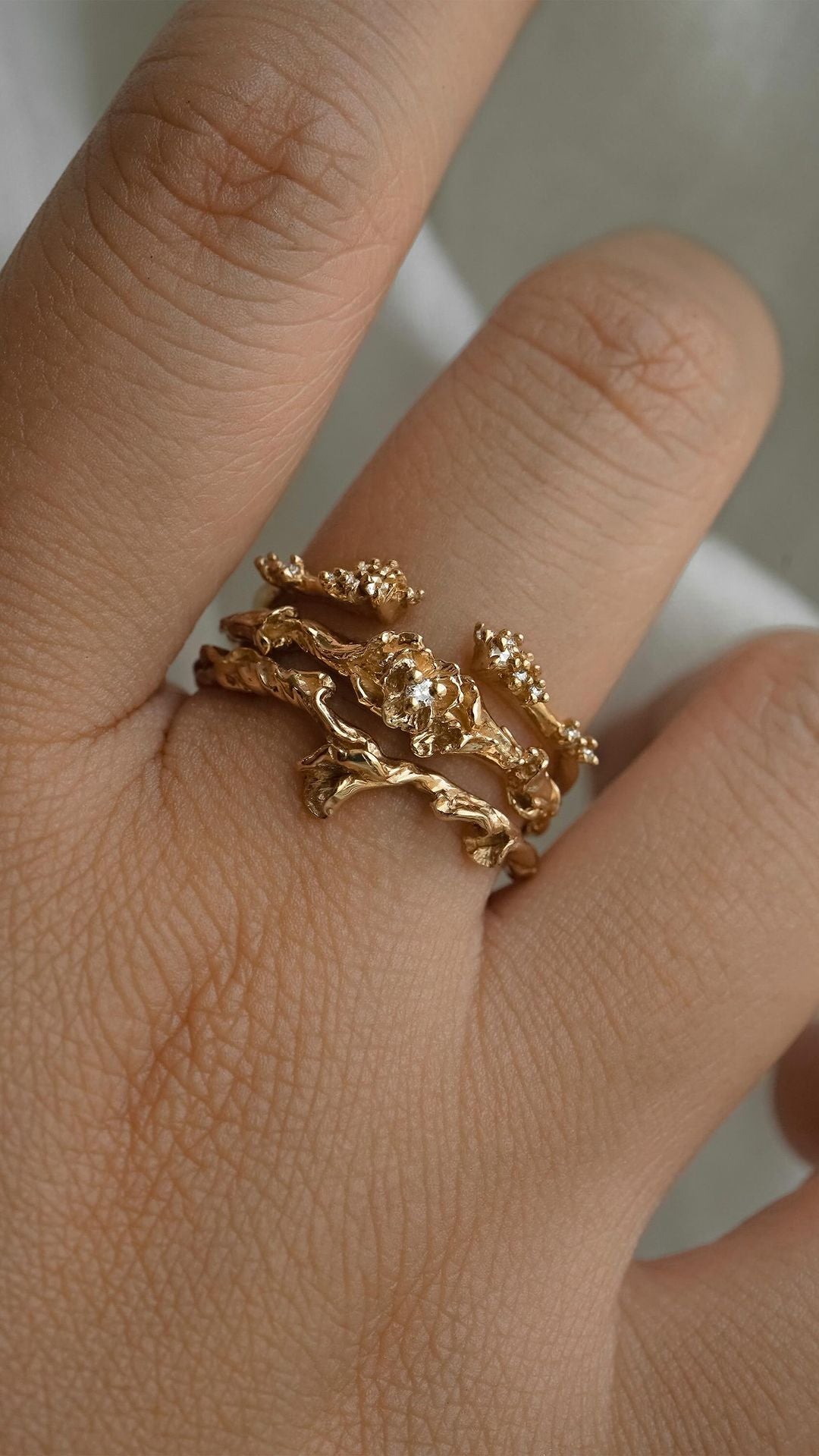 A close up of a hand wearing three rings on the same finger. From top to bottom: The Daphne Cuff Band, the Pansy Signet Ring, and the Evening Fleur - Laurie Fleming Jewellery