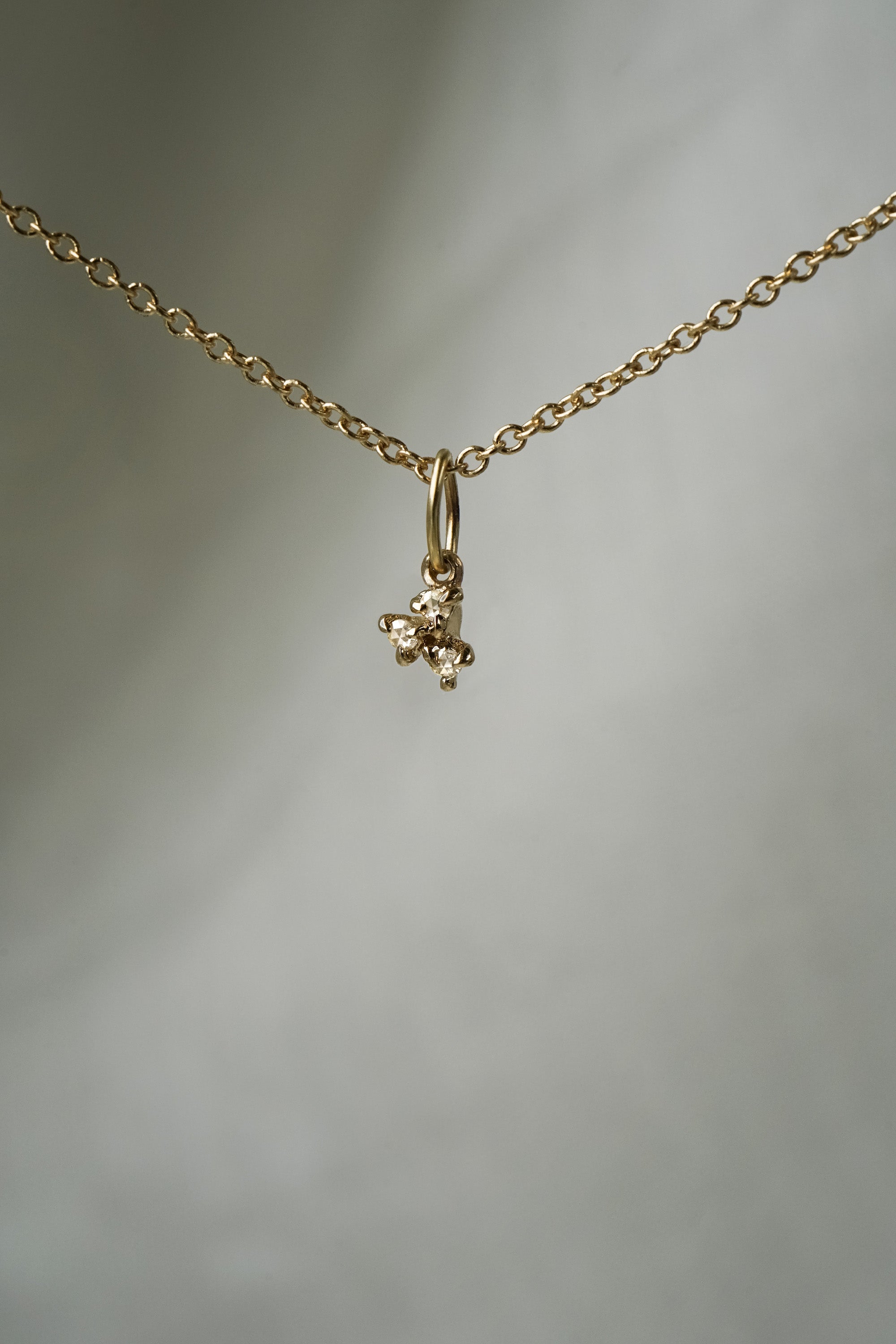 A diamond dewdrop charm, featuring a cluster of three rose cut diamonds,  hanging from a 1mm cable chain with smooth oval links. Handmade in Toronto by Laurie Fleming Jewellery.