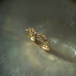 A close up of two rings held nestled together standing on an oyster dish. The top ring is a diamond Jasmine ring featuring marquise cut diamonds on the band and a gently pointed centre. The centre fits perfectly into the subtle dip of the Sylph band, which features rose cut and round brilliant cut diamonds along the band. Both rings are solid gold and handcarved by Laurie Fleming Jewellery.