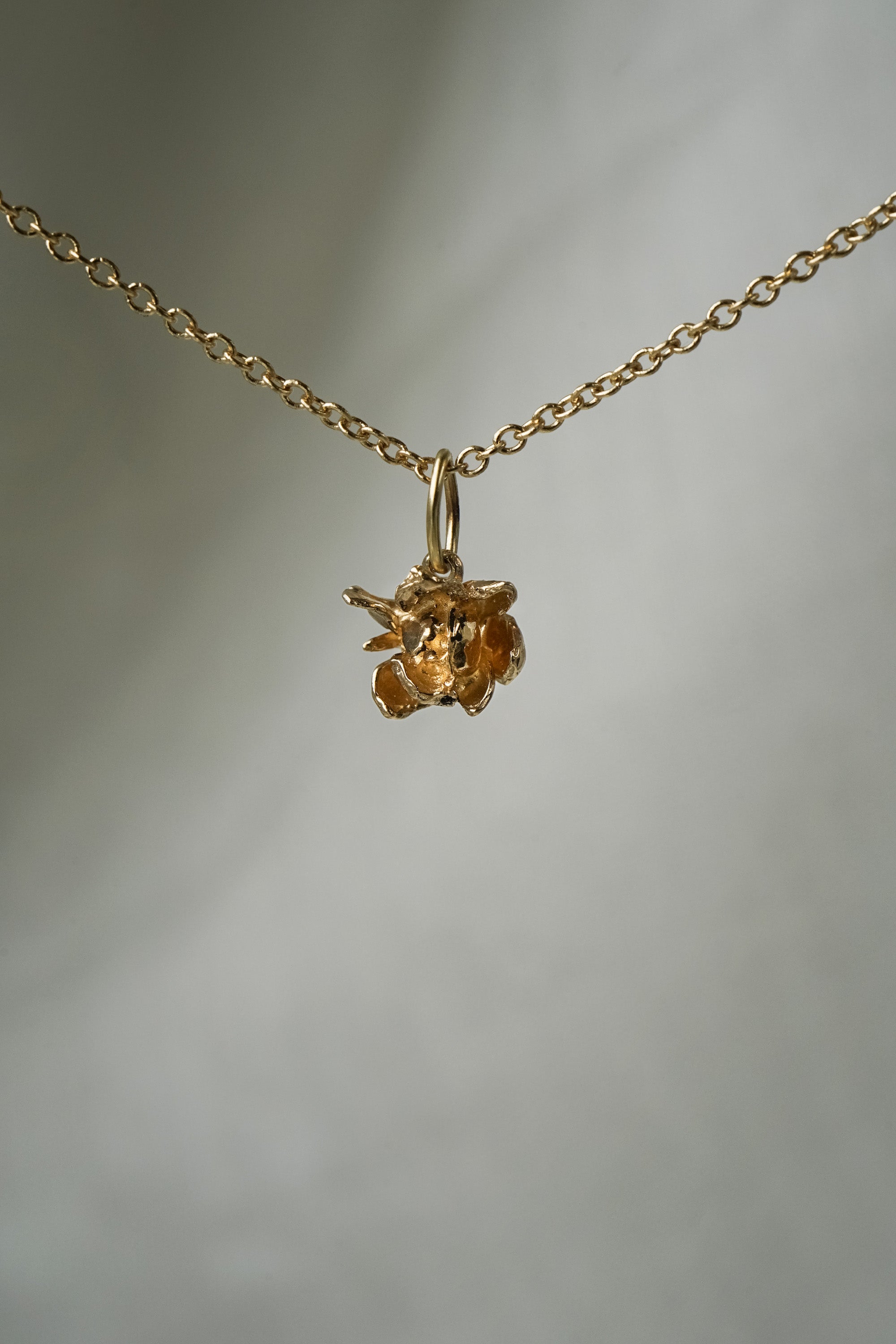 A hand-carved, solid gold blooming Lotus flower charm,  hanging from a 1mm cable chain with smooth oval links. Handmade in Toronto by Laurie Fleming Jewellery.