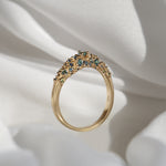 Laurie Fleming Jewellery's "Moss Signet Ring," a bold solid gold signet-style ring encrusted with varying shades and sizes of blue-green teal sapphires on the band.