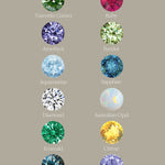 A chart with a light taupe background depicting the different birthstone gems that are available in the Laurie Fleming Jewellery "Pansy" collection. Each stone is labelled with white text. From the top left: Tsavorite Garnet, Ruby, Amethyst, Peridot, Aquamarine, Sapphire, Diamond, Australian Opal, Emerald, Citrine, Alexandrite, and Tanzanite.