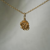 A hand-carved ranunculus flower charm,  hanging from a 1mm cable chain with smooth oval links. Handmade in Toronto by Laurie Fleming Jewellery.