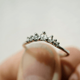 A white gold rose cut diamond Beacen ring held in a hand.