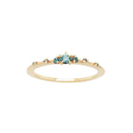 Laurie Fleming Jewellery's "Sapphire Water Lily Ring," a delicate solid gold stacking ring with blue-green teal sapphires scattered along the band. The ring is on a white background.