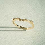 The Sylph Band ring by Laurie Fleming Jewellery, which features a subtly curved band to fit contour around another ring. The band features round brilliant and rose cut diamonds. It is resting against a white background.
