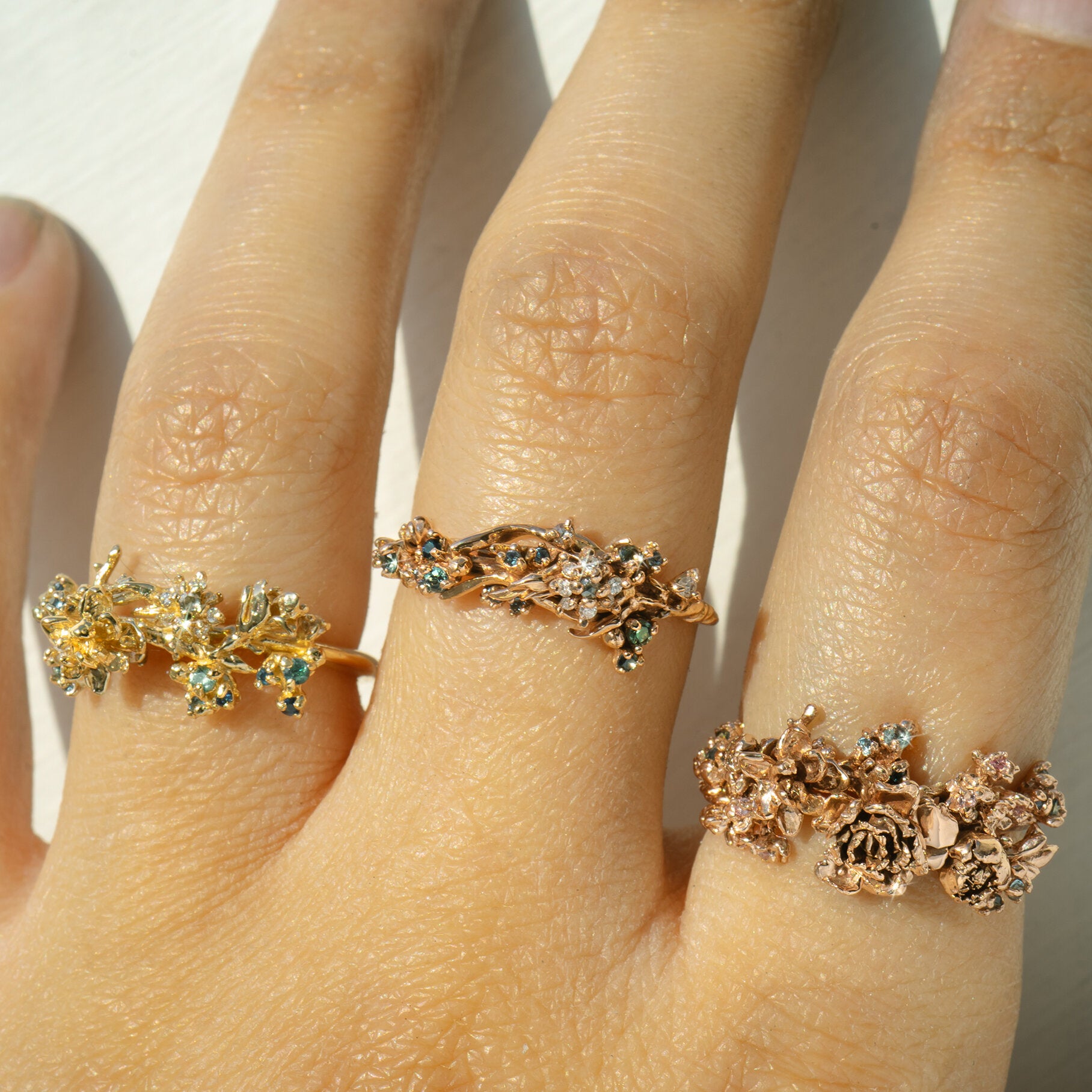 Three Asrai Garden Rings worn on one hand, including elements such as moss, magnolia branch, anemone, peonies, etc - Laurie Fleming Jewellery