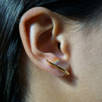 A close-up of an ear showing one of the possible ways to wear the hand-carved sculptural solid gold "Versare" earrings by Laurie Fleming Jewellery.